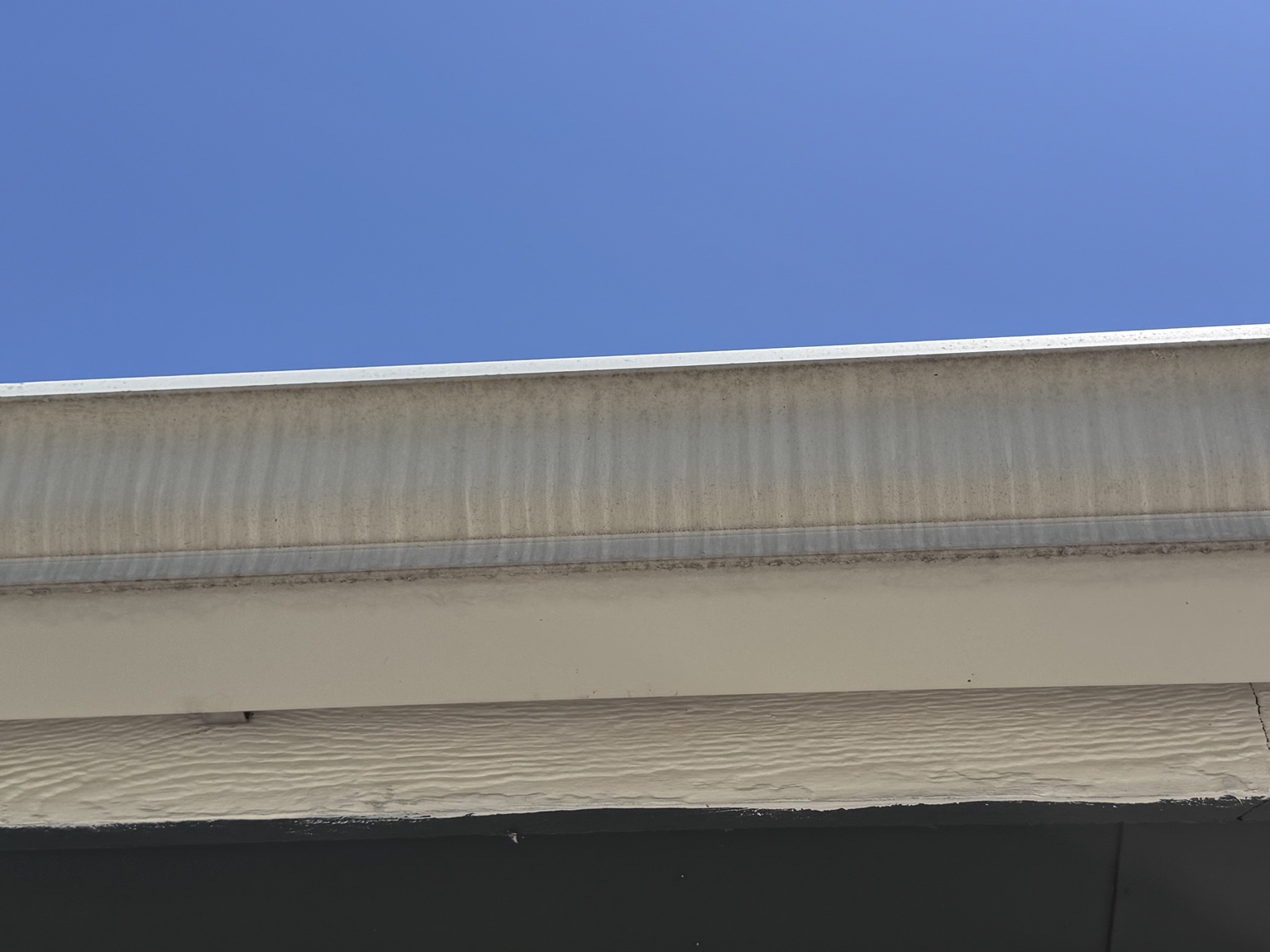 Dark vertical staining across the exterior face of a residential gutter